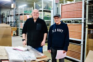 Two people smiling while going through materials at Onward Manufacturing. One is supported through KW Career Compass.