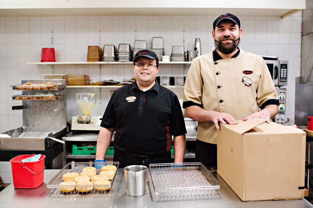 Two people supported by KW Career Compass working at Tim Hortons preparing donuts.