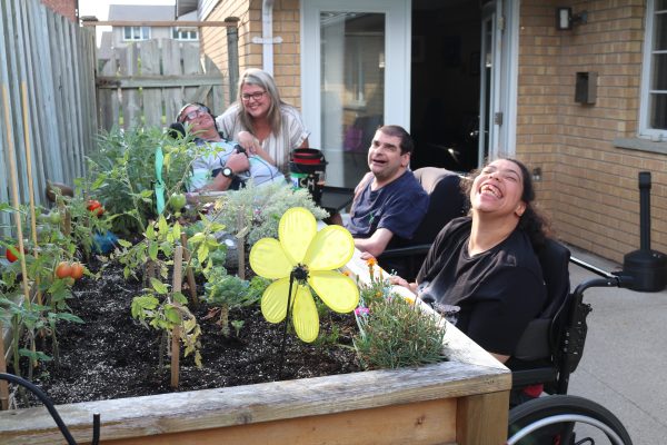Tracey Riley by the raised flowerbed with people we support at KWH