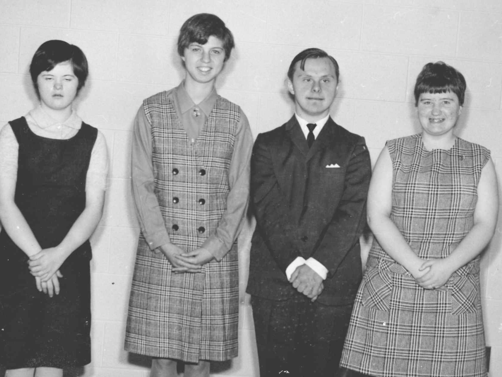 Photo of four people dressed up and smiling in a row.