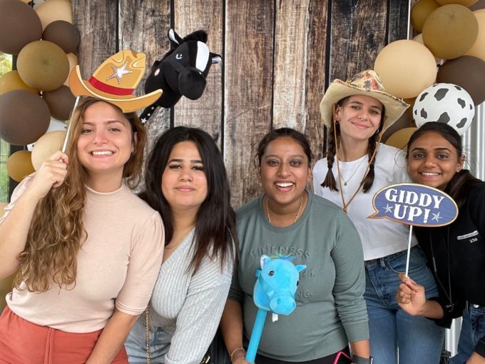 Five Direct Support Worker staff members from KW Habilitation smiling and posing with cowboy hats and horses at the 2023 Staff Appreciation event.