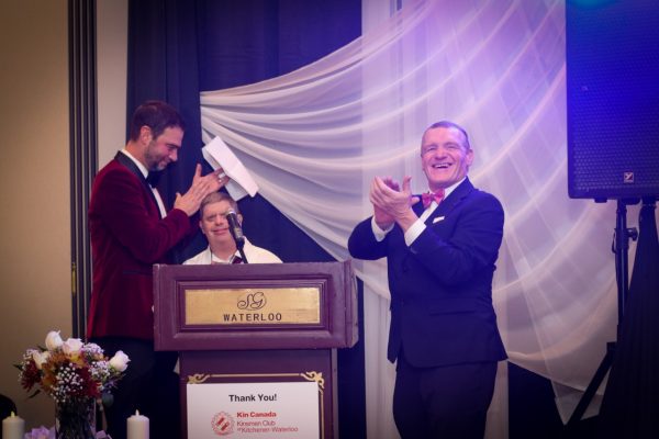 Adult with a disability with KW Habilitation Board Member at the podium clapping during our 2022 Gala celebrating 50 years at KW Habilitation.
