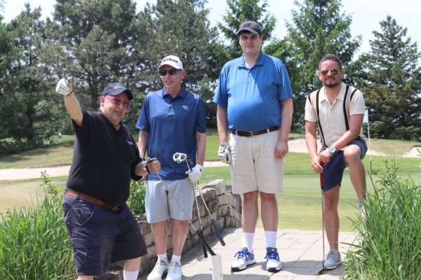 Two staff members from KW Habilitation and two adults with disabilities posing with their golf clubs at KW Habilitation's 2023 Annual Golf Tournament.
