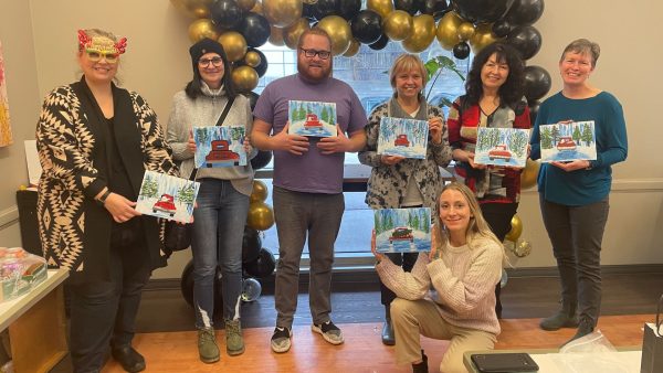 7 people from Early Learning smiling while holding their Christmas paintings.