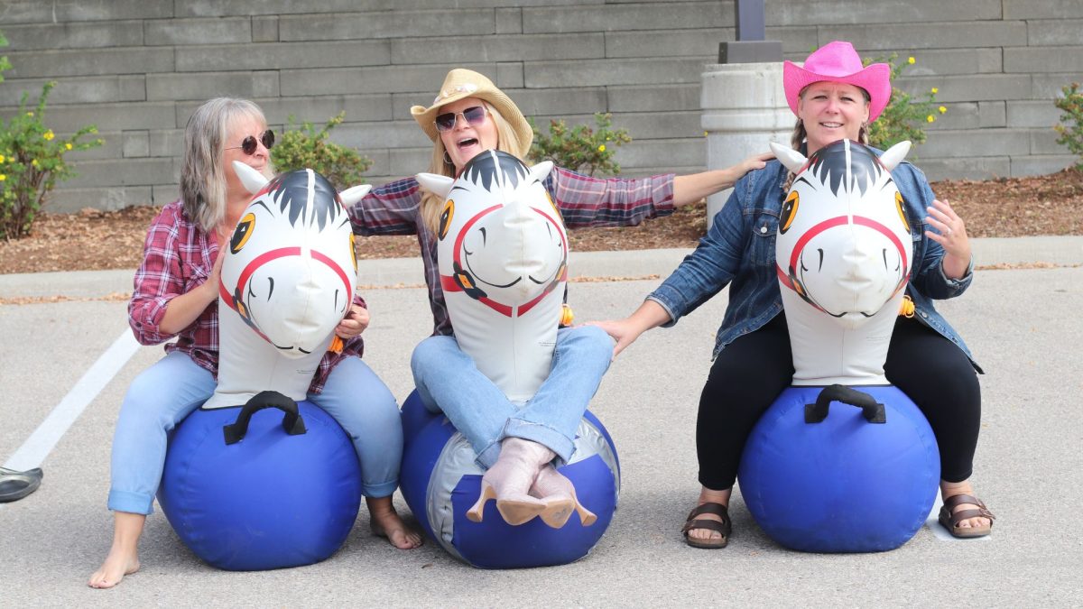 Three ladies from our Early Learning leadership team riding inflatable horses.
