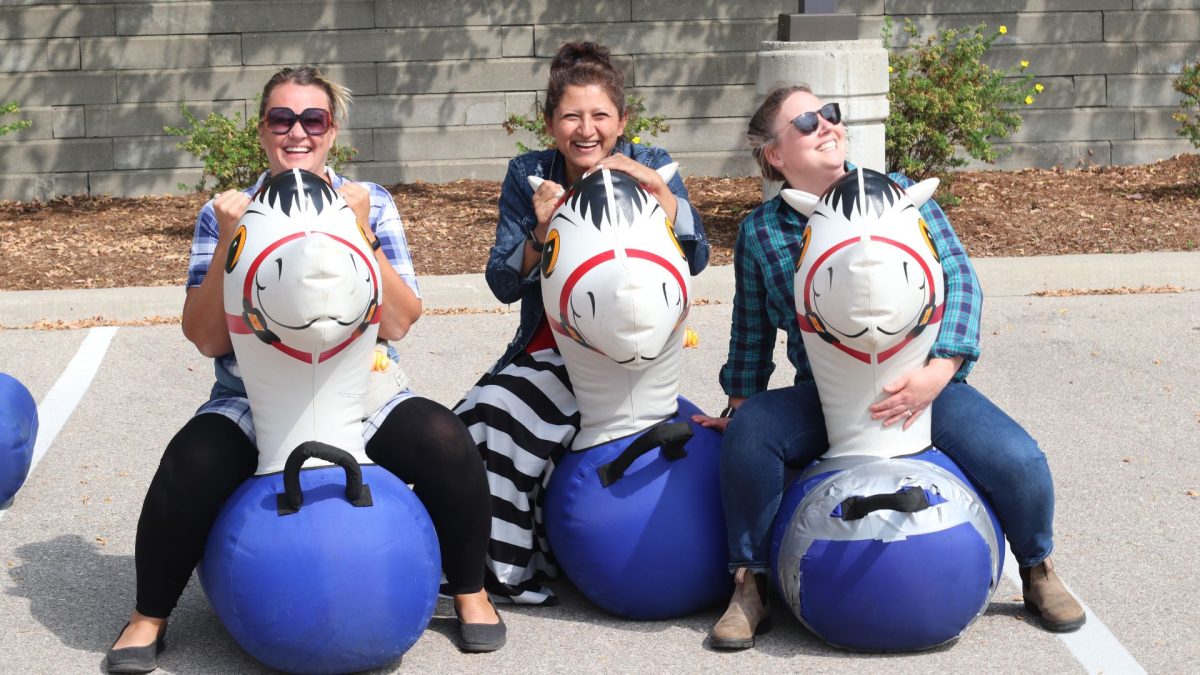 Three ladies from our Early Learning team riding inflatable horses.