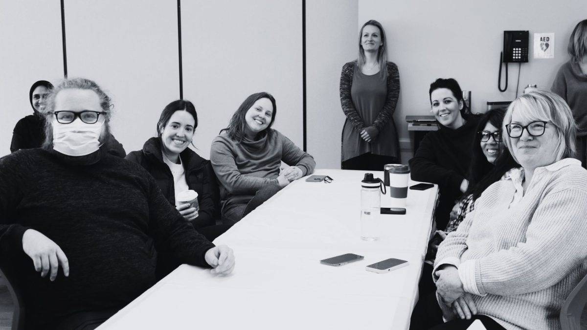 8 people from Early Learning smiling during a team meeting in the Bullas Hall.