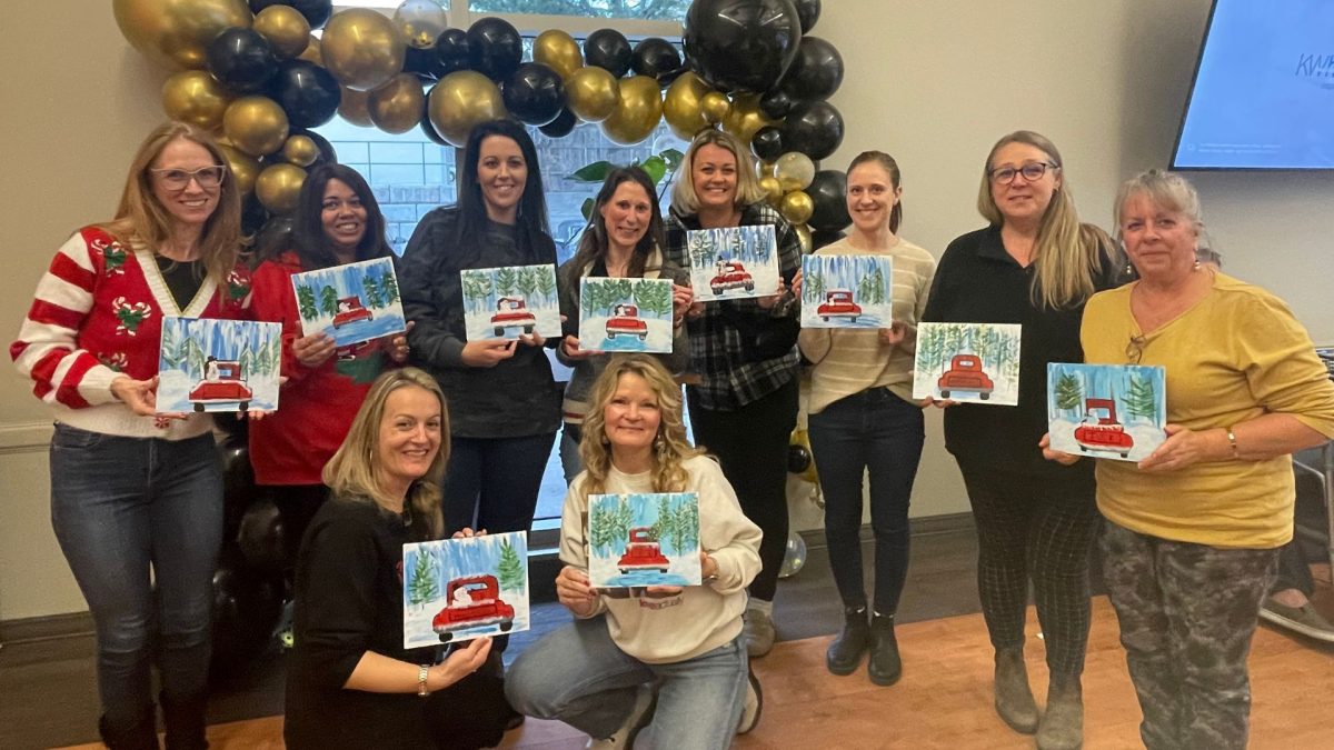 10 people from Early Learning smiling while holding their Christmas paintings.