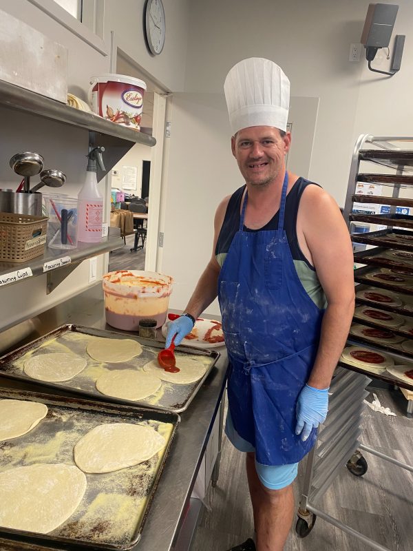 MicrosoftTeams-image (3) David making pizzas and smiling wearing a blue apron and white chef hat.
